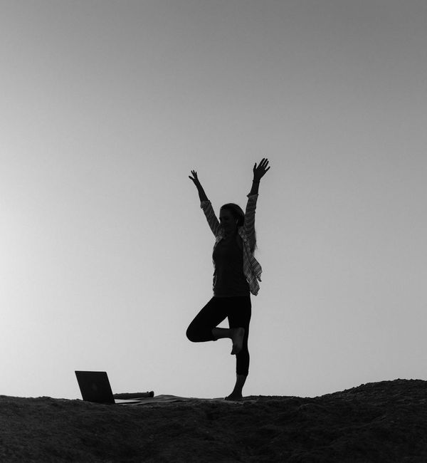 Silhouette of a person stretching during sunrise, feeling energized.